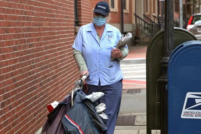 a usps postal worker wears mask while making deliveries in beacon hill in boston during the covid 19 pandemic on april 8 2020